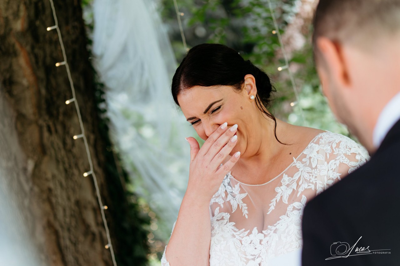 La sposa ride coprendosi la bocca con la mano davanti allo sposo